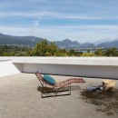 Taras wyłożony matowymi, beżowymi płytkami imitującymi kamień, Marazzi Caracter Mix Beige Str MDS2 100x100 cm, w centrum którego stoi drewniany leżak