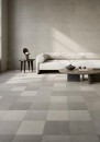 Nowoczesny salon z jasną sofą i płytkami podłogowymi imitującymi beton, w różnych odcieniach szarości Fioranese Ogi MIX Grigio Naturale 30,2x30,2
