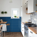 Kuchnia z niebieskimi płytkami ściennymi oraz szafkami kuchennymi nad którymi wyłożono matowe płytki dekoracyjne Marazzi Cloud Mandala Ice