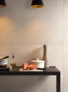 Wnętrze z brązowym stołem przymocowanym do ściany i kremowymi płytkami ściennymi imitującymi beton Porcelanosa Santorini Bone
