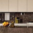 Kuchnia z białymi wiszącymi szafkami, wyłożona połyskującymi brązowymi płytkami imitującymi marmur Marazzi Grande Marble Look Emperador Lux