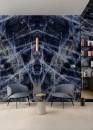 Studio do wywiadu ze ścianą wyłożoną połyskującymi niebieskimi płytkami imitujacymi marmur Marazzi Grande Marble Look Sodalite Blu Lux, dwoma fotelami oraz stolikiem kawowym