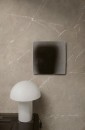 Ściana wyłożona matowymi szarymi płytkami imitującymi marmur Marazzi Grande Marble Look Tafu Matt, przy której stoi szafka z białą lampką