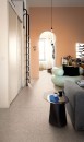 Stylowy salon z wygodną sofą i minimalistycznym wystrojem, w pokoju znajduje się również lustro, rośliny doniczkowe i nowoczesne lampy, natomiast podłoga wyłożona jest płytkami lastryko Marazzi Frammento Micro Cotto R10