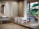 Łazienka z wyjściem na taras, białą wanną wolnostojącą, złotymi bateriami oraz beżowymi płytkami ścienno-podłogowymi marmuropodobnymi Porcelanosa Beige Velluto Polished