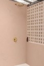 Łazienka z różowymi ścianami wykończonymi płytkami Marazzi Grande Resin Look Rosa Antico Satin, złotą armaturą i ażurową ścianka działową dodającą wnętrzu elegancji