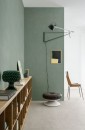 Aranżacja wnętrza z płytkami Marazzi Grande Resin Look Verde Salvia Satin na ścianie, wraz z obrazem w czarnej ramie i designerską lampą dodającymi wnętrzu koloru i charakteru