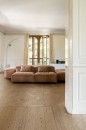 Płytki Marazzi Intrecci Nocciola 20x120 MF7F na podłodze w salonie z beżową sofą i dużymi oknami, naturalny wzór drewna dodaje wnętrzu przytulności