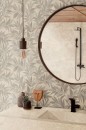 Aranżacja łazienki z płytkami Marazzi Limestone Wall Decoro Agrifoglio Sand Touch 40x120 MFDT na ścianie, okrągłe lustro i czarna armatura stanowią stylowe akcenty w jasnym wnętrzu