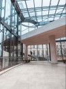 Płytki Marazzi Market New Cement White na podłodze w przestronnym holu z metalową konstrukcją i szklanym dachem, biały odcień i delikatna struktura betonu dodają wnętrzu elegancji