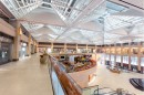 Przestronne wnętrze galerii handlowej z podłogą wyłożoną płytkami Marazzi Market New Stone Beige imitującymi beton, ciepły, beżowy odcień płytek nadaje wnętrzu elegancki i nowoczesny charakter