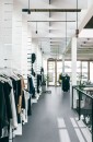 Aranżacja sklepu odzieżowego z wykorzystaniem płytek Marazzi Market New Sand Silver 60x60 M9RF na podłodze, białe ściany i metalowe wieszaki stanowią stylowe akcenty w jasnym wnętrzu