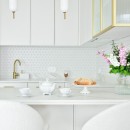 Kuchnia z białymi frontami, złotą baterią oraz białymi płytkami ściennymi Raw Decor Constellation White z jasną fugą