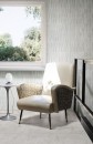Nowoczesna aranżacja wnętrza z jasnoszarą podłogą wykonaną z płytek Marazzi Naturalia Bianco 60x60 cm o subtelnej teksturze, w pomieszczeniu znajduje się elegancki fotel w odcieniach beżu, a obok niego stoi minimalistyczny stolik z białą, kulistą lampą