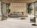 Przestrzenny salon z szarą sofą i fotelami oraz beżowymi płytkami podłogowymi imitującymi kamień Porcelanosa Colorado Bone