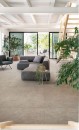 Salon wyłożony szarymi płytkami imitującymi kamien Marazzi Naturalia Taupe 100x100 cm, z dużą szarą kanapą , ustrojony ozdobnymi kwiatami