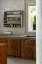 Fragment rustykalnej kuchni, gdzie ściana pokryta jest płytkami Marazzi Naturalia Decoro Incisione Grigio Touch 33x100 MENN o delikatnym, jasnym wzorze przypominającym subtelny rytowany motyw kwiatowy, na ścianie wisi stara, drewniana półka z przyprawami