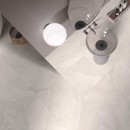 Widok na łazienkę z góry, widać tutaj umywalkę, lustro oraz lampę przymocowane do ściany a na podłodze są położone płytki gresowe Ceramiche Italiane Alpen Slate Bone Matt 60x60