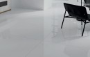 Fragment salonu na którym widać czarne metalowe krzesło oraz płytki Vitacer Narvik Silver Pulido 59x119