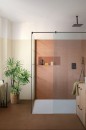 Stylowa łazienka z prysznicem typu walk-in, gdzie główny element dekoracyjny stanowi ściana wyłożona brązowymi płytkami Marazzi Racconti Terracotta Struttura 3D Segmenti 30x90 cm MCYY, z widoczną wnęką na kosmetyki