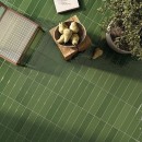 Drewniany stolik z miską wypełnią gruszkami, obok stoi drewniane krzesło a po drugiej stronie kwiatek, to wszystko na podłodze gdzie położone są płytki Vives Zero Origo Green 8,0x31,5