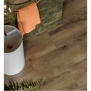 Brązowa, gresowa płytka podłogowa imitująca drewno Stargres Taiga Wood Brown 30x120 w wykończeniu matowym położona na podłodze w towarzystwie zielonych płytek na ścianie