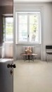 Minimalistyczne wnętrze z podłogą z płytek Marazzi SistemS Sand 60x60 MQYT, podkreślającą naturalne światło wpadające przez duże okno z białymi ramami i parapetem, na którym stoi ozdobna rzeźba