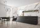 Gresowa płytka imitująca marmur w białym kolorze Cerrad Calacatta White Matt Rect. 59,7x119,7 w wykończeniu powierzchni matowym, położona na ścianie w kuchni z ciemnymi szafkami oraz ciemnym stołem i krzesłami z którymi kontrastuje
