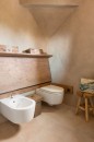 Nowoczesna toaleta z podłogą wyłożoną beżowymi płytkami strukturalnymi Marazzi Slow Calce Strutturato 60x60 cm MFSU, imitującymi beton, oraz podwieszaną miską WC i bidetem