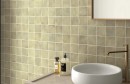 Płytka ścienna, cegiełka w kolorze oliwkowym, Equipe Sabbia Weald Green 10x10, położona na ścianie w łazience na której wisi lustro z drewnianą ramką oraz półka na której stoi biała umywalka wraz z kosmetykami