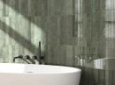 Płytka ścienna monokolorwa w kolorze zielonym w połysku, Equipe Verticale Oakmoss 5x40, położona w łazience na ścianie przy której znajduje się duża, biała owalna wanna