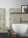 Płytka ścienna, cegiełka w kolorze zielonym w połysku, Equipe Verticale Green Field 10x10, położona w nowoczesnej łazience w której znajduje się duża wolnostojąca wanna a na ścianie znajduje się półka na kosmetyki oraz ozdoby