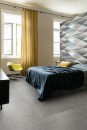 Sypialnia z multikolorowymi płytkami dekoracyjnymi z geometrycznym wzorem Marazzi White Deco Vision Touch 60x180 cm ME0N na ścianie akcentowej, tworzącymi nowoczesne i dynamiczne tło dla łóżka