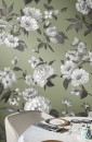 Zielona ściana wyłożona płytkami dekoracyjnymi z motywem kwiatowym Marazzi White Deco Decoro Roseto Touch 60x180 cm MF97, z białymi różami i szarymi liśćmi, widoczne częściowo nakryty stół i krzesł