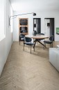 Nowoczesny salon z minimalistycznym designem i drewnopodobną podłogą z płytek Marazzi Vivo Sabbia Chevron 11x54 cm MP3P, które nadają wnętrzu ciepła i wyrafinowania