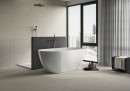 Płytka ścienna w kolorze beżowym o matowym wykończeniu Cifre Acron Raine Ivory Mate Xs Rect. 40x120, położona na ścianie w łazience w której znajduje się owalna duża, biała wanna oraz duże przestronne okno z ciemnymi ramami