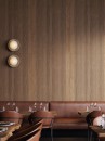 Wnętrze restauracji ze skórzanymi brązowymi fotelami oraz płytkami ściennymi drewnopodobnymi z efektem boazerii Porcelanosa Stripe 3D London Nogal 59,6x150 100371160
