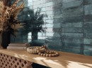 Na ścianie położone są płytki cegiełki Cifre Feel Turquoise Brillo 6x26, przy ścianie stoi półka z książkami oraz kwiatami