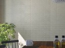 W pomieszczeniu znajduje się wisząca lampa, kwiatek oraz drewniany stół a na ścianie położone są płytki Cifre Granite Elven Grey Mate 25x75