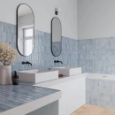 Gresowa dekoracyjna niebieska płytka Gayafores Deco Artis Blue 32x62,5 na ścianach i blatach jasnej, przestronnej łazienki z czarną armaturą oraz lustrami w czarnej ramie