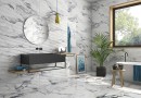 Płytka gresowa, podłogowa imitująca biały marmur, wykończenie powierzchni w połysku. Geotiles Valeria Plata Rect. 60x120, położona w łazience na podłodze w której znajduje się biała wanna, wiszące lustro wraz z czarną umywalką oraz okno z widokiem ogród