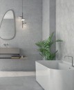 Płytka gresowa, podłogowa w kolorze białym, wykończenie powierzchni matowe, Geotiles Argon Blanco Natural Rect. 60x60 położona na ścianie w łazience w której znajduje się duża biała wanna oraz umywalka a nad nią wiszące lustro