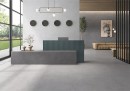 Płytka gresowa, podłogowa w kolorze szarym, wykończenie powierzchni matowe, Geotiles Talo Perla Mate Rect. 90x90 położona na ścianie w nowoczesnym salonie, w którym znajduje się wypoczynek w jasnym kolorze, obraz na ścianie oraz okna z widokiem na ogród