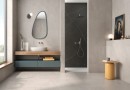 Płytka gresowa, podłogowa w kolorze kremowym imitująca kamień, wykończenie powierzchni matowe, Geotiles Eddystone Blanco Mate Rect. 60x60 położone w łazience, w której znajduje się prysznic, szafka na ręczniki, biała umywalka oraz wiszące lustro