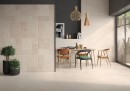 Płytka gresowa, podłogowa w kolorze beżowym, wykończenie powierzchni matowe strukturalne, Geotiles Montpellier RLV Marfil Matt Rect. 60x120 położona na ścianie w pomieszczeniu gdzie znajduje się stół, krzesła, lampa wisząca oraz okno z widokiem na ogród
