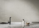 Płytki podłogowe, gresowe imitujące kamień w kolorze szarym, wykończenie powierzchni matowe, Cerrad Softstone Pearl Rect. 59,7x119,7, położone na ścianie w kuchni gdzie znajduje się zlewozmywak oraz płyta indukcyjna na blacie