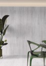 Płytka gresowa, podłogowa imitująca beton w kolorze szarym, wykończenie powierzchni matowe, Cerrad Dignity Light Grey Rect. 59,7x119,7 położona na ścianie w pomieszczeniu gdzie znajduje się kwiat oraz zielone krzesło