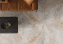 Płytka gresowa, podłogowa imitująca kamień, wykończenie powierzchni matowe, Cerrad Auric Light Grey Rect. 59,7x59,7 położona w pomieszczeniu na podłodze gdzie znajduje się kanapa oraz ciemny stolik