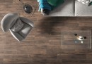 Płytka gresowa, podłogowa imitująca drewno w kolorze brązowym, wykończenie powierzchni matowe, Cerrad Tonella Brown 19,3x120,2 położona na podłodze w pokoju gdzie znajduje się fotel, kanapa oraz szklany stolik