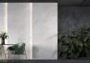 Płytka gresowa, podłogowa imitująca kamień w kolorze szarym, wykończenie powierzchni satynowe, Cerrad Distinct White Silky Cristal 59,7x119,7 położona na ścianie w pomieszczeniu gdzie znajduje się stolik z krzesłem oraz kwiaty